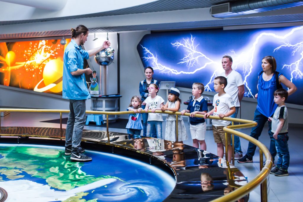 Parents and kids watch a demonstration at a science museum.