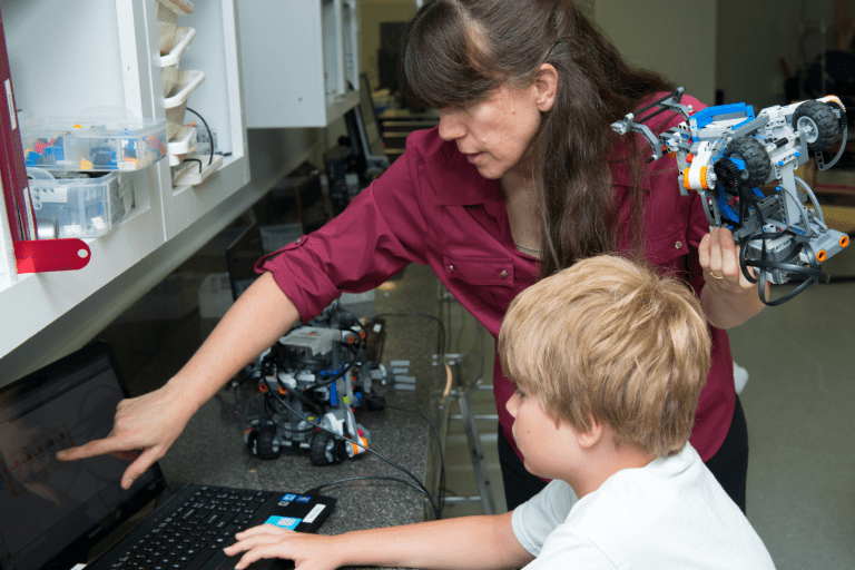 A robotics instructor teaching a student how to code